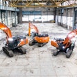 Three Hitachi excavators parked inside an industrial building