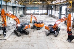 Three Hitachi excavators parked inside an industrial building