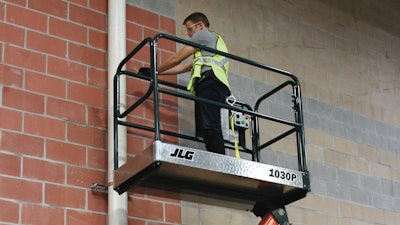 Worker using JLG 1030P low-level access lift to work on a pipe