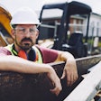Construction worker standing in front of a mini excavator