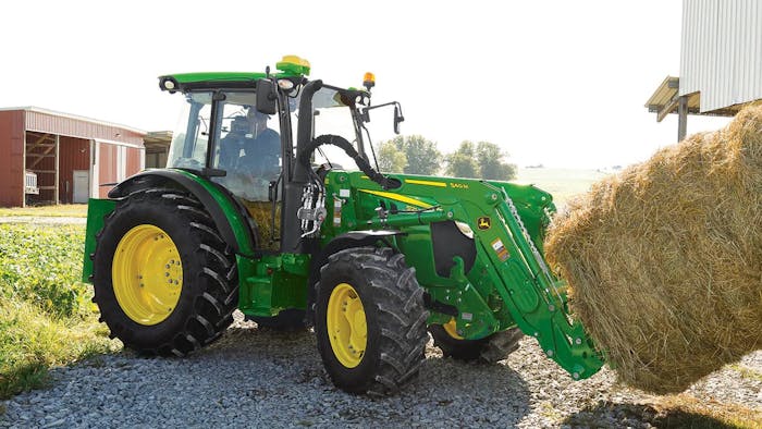 John Deere 5M Series tractor hauling a hay bale