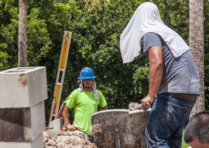 Construction workers working in extreme heat with a wet towel on their heads