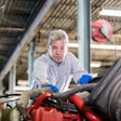 Diesel technician standing over a piece of heavy equipment
