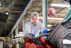 Diesel technician standing over a piece of heavy equipment