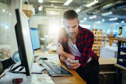 Blue collar worker texting at a standing desk