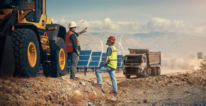 Construction workers on a jobsite with solar panels and windmills.