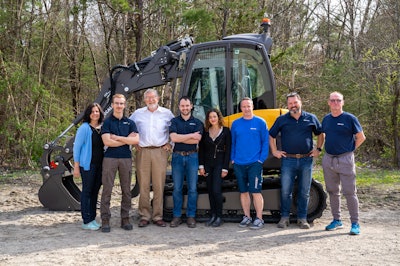 Mecalac sales and service employees standing in front of a compact excavator
