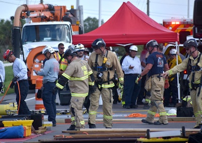 Firefighters preparing wood beams to shore up a trench.