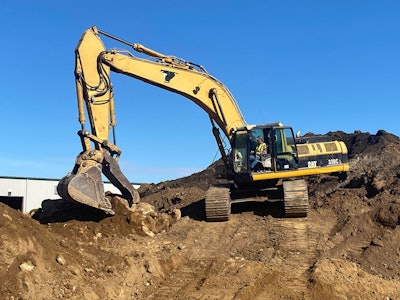Cat excavator digging through a pile of dirt