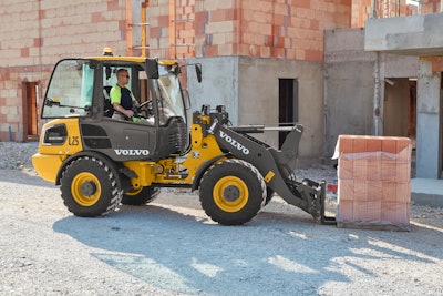 Volvo L25 Electric compact wheel loader picking up stack of bricks with forks