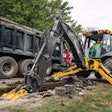 John Deere backhoe digging beside a road