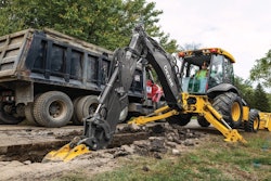 John Deere backhoe digging beside a road