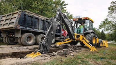 John Deere backhoe digging beside a road