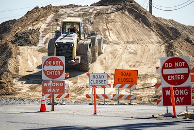 Dozer moving down a hill with wrong way directional signs all around