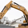 Cat 336 excavator dumping bucket load into dump truck from position atop dirt pile.