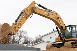 Cat 336 excavator dumping bucket load into dump truck from position atop dirt pile.