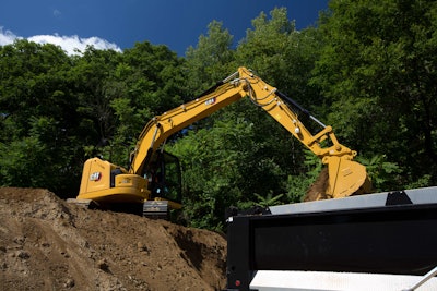 Cat 315 GC excavator on dirt pile dumping bucketful in truck bed