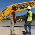 Two workers review points where the Smart Construction retrofit comes into play on a Komatsu excavator.