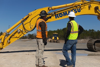 Two workers review points where the Smart Construction retrofit comes into play on a Komatsu excavator.