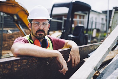 Construction worker standing at a fence on a jobsite