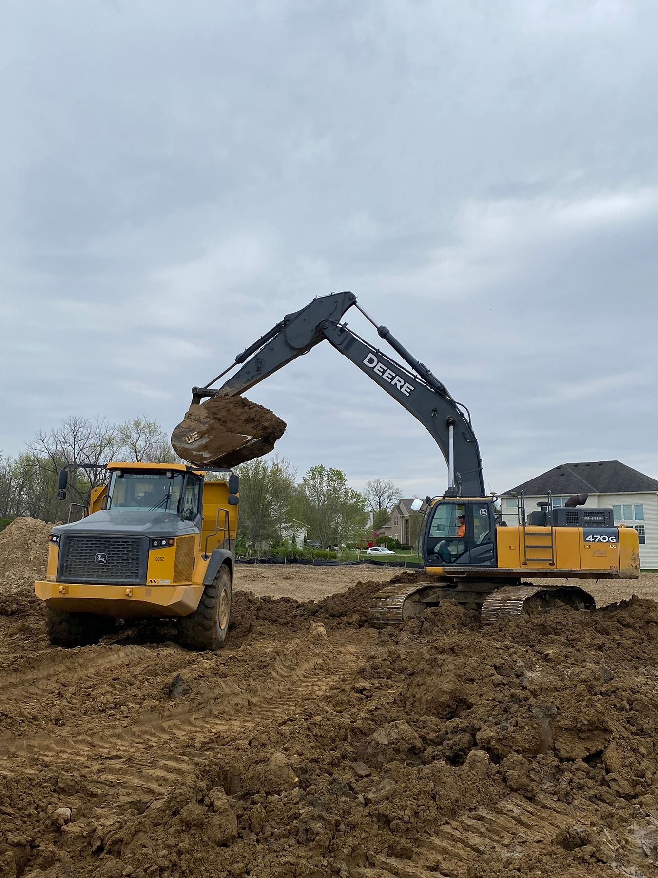 Werk Brau excavator 6 yard bucket poised with full bucket load on Deere excavator over Deere dump truck