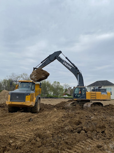 Werk Brau excavator 6 yard bucket poised with full bucket load on Deere excavator over Deere dump truck