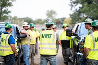 Veit Construction workers standing by trucks while talking