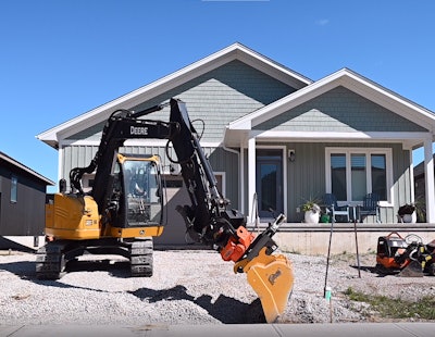 AMI Attachments AXXIS tiltrotator with bucket on Deere excavator digging gravel in front of house