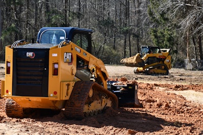 Cat 279D3 compact track loader rear view pushing red clay Cat 259D3 background hauling red clay in bucket