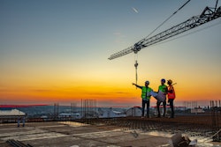 Workers talking at construction site reviewing plans