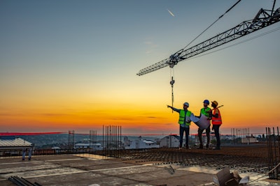 Workers talking at construction site reviewing plans