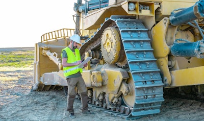 Construction worker standing next to dozer