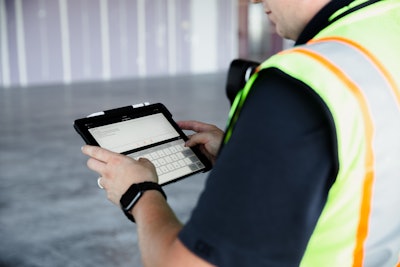 Construction worker holding tablet using Raken app