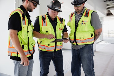 Three construction workers review data on tablet