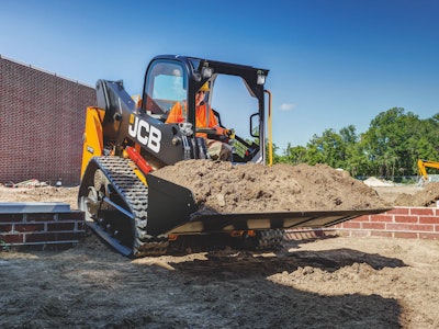 JCB 215T compact track loader full bucket dirt in front of red brick wall