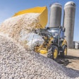 John Deere G-tier wheel loader dumping at a rock pile.