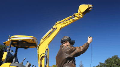 SRI International robot excavator operator with virtual reality goggles raises arm and excavator raises arm