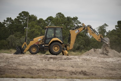 Caterpillar 420XE backhoe loader scooping dirt