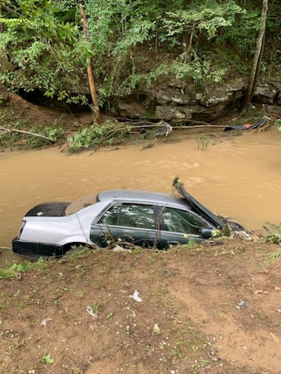 kentucky floods car over muddy bank of swollen brown water creek