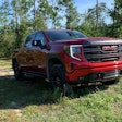 2022 GMC AT4X pickup truck red parked on dirt road in woods