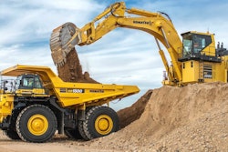 Komatsu HD1500 rigid-frame dump truck being loaded by Komatsu excavator on top of dirt pile