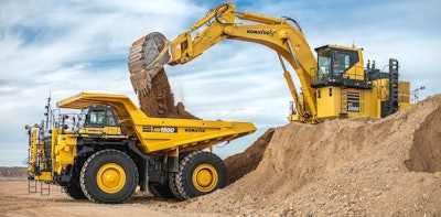 Komatsu HD1500 rigid-frame dump truck being loaded by Komatsu excavator on top of dirt pile