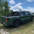 2022 Nissan Frontier Pro-4X pickup truck tactical green color side view parked on grassy hill with trees in background