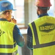 Two workers wearing B2W safety vests and hard hats