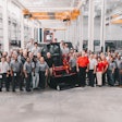 Takeuchi employees stand next to a compact track loader manufactured in Moore, South Carolina