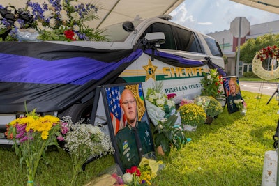 Pinellas County Sheriff's cruiser decorated with flowers, cloth, portrait of Deputy Mike Hartwick who died when hit by wheel loader