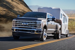2023 Ford Super Duty F-350 Lariat brown towing covered trailer on desert mountain road