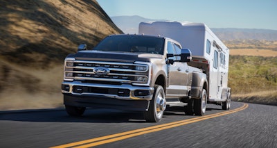 2023 Ford Super Duty F-350 Lariat brown towing covered trailer on desert mountain road