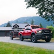 red 2023 Ram 2500 Rebel diesel towing ATVs with home and mountains in background