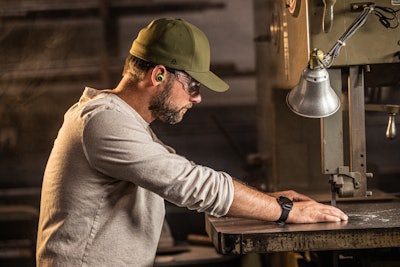 Man at bandsaw with earbuds